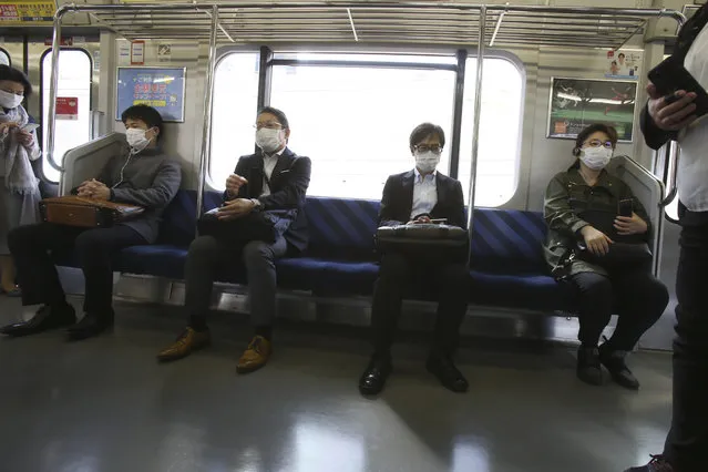 Passengers wearing face masks to protect against the spread of the new coronavirus ride on a train in Yokohama near Tokyo, Wednesday, April 8, 2020. (Photo by Koji Sasahara/AP Photo)