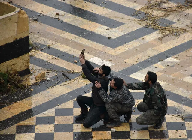 Syrian pro-government forces take a selfie in the courtyard of the ancient Umayyad mosque in the old city of Aleppo on December 13, 2016. After weeks of heavy fighting, regime forces were poised to take full control of Aleppo, dealing the biggest blow to Syria's rebellion in more than five years of civil war. (Photo by George Ourfalian/AFP Photo)