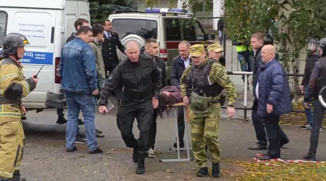 In this image taken from video, servicemen carry a wounded person from the scene of a shooting at school No. 88 in Izhevsk, Russia, Monday, September 26, 2022. (Photo by Izhlife.ru via AP Photo)