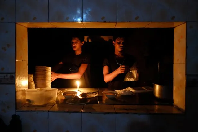 Staff at an eatery work by candle light after a failure in Bangladesh's national power grid plunged much of the country into a blackout in Dhaka, Bangladesh, Tuesday, October 4, 2022. (Photo by Mahmud Hossain Opu/AP Photo)