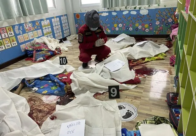 A first responder prays over one of numerous bodies at the site of an attack in a day care center, Thursday, October 6, 2022, in the town of Nongbua Lamphu, north eastern Thailand. A former policeman facing a drug charge burst into a day care center in northeastern Thailand on Thursday, killing dozens of preschoolers and teachers before shooting more people as he fled in the deadliest rampage in the nation’s history. (Photo by Mungkorn Sriboonreung Rescue Group via AP Photo)