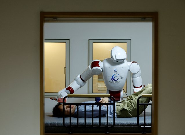 AIREC, an artificial intelligence (AI)-driven humanoid robot, demonstrates a manoeuvre for changing diapers or preventing bedsores with a researcher at Waseda University's laboratory in Tokyo, Japan on February 17, 2025. (Photo by Kim Kyung-Hoon/Reuters)