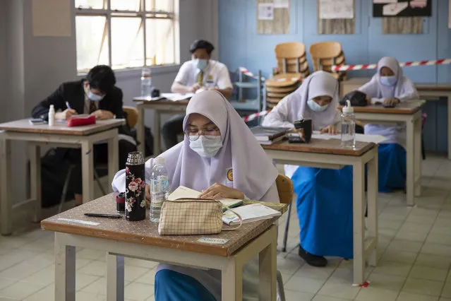 Students wearing face masks and maintaining social distancing at a classroom during the first day of school reopening at a high school in Putrajaya, Malaysia, Wednesday, June 24, 2020. Malaysia began reopening schools Wednesday while entering the Recovery Movement Control Order (RMCO) after three months of coronavirus restrictions. (Photo by Vincent Thian/AP Photo)