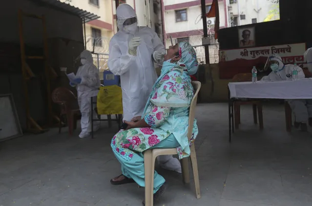A health worker takes a swab test of a woman during a free medical checkup in Dharavi, one of Asia's biggest slums, in Mumbai, India, Friday, June 26, 2020. India is the fourth hardest-hit country by the pandemic in the world after the U.S., Russia and Brazil. (Photo by Rafiq Maqbool/AP Photo)