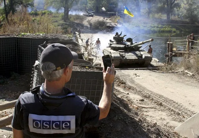 A member of the Organization for Security and Co-operation in Europe (OSCE) monitors the withdrawal of tanks of the Ukrainian armed forces near the village of Nyzhnje in Luhansk region, Ukraine, October 5, 2015. Ukraine has started withdrawing tanks and light artillery from the frontline in the eastern region of Luhansk in accordance with a recent agreement with pro-Russian separatists, the Ukrainian military said on Monday. (Photo by Reuters/Stringer)