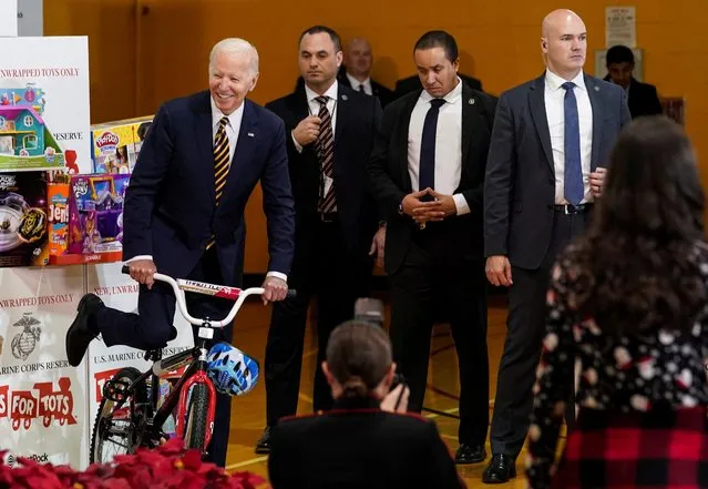 Members of U.S. President Joe Biden's security detail stand by as President Biden pretends to ride a bike while arriving for the U.S. Marine Corps Reserve Toys for Tots event at Joint Base Myer-Henderson Hall in Arlington, Virginia, U.S., December 12, 2022. (Photo by Kevin Lamarque/Reuters)