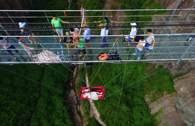 Newlyweds take wedding photos hanging from bridge, Yueyang, Hunan province, China on August 9, 2016. (Photo by Top Photo Corporation/Rex Features/Shutterstock)