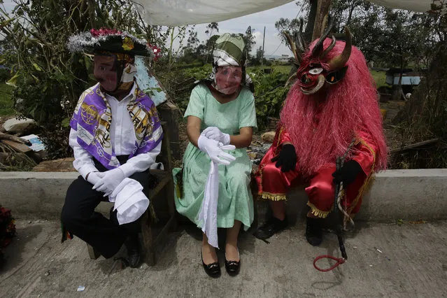 People dressed in costumes take a break during the traditional New Year's festival known as “La Diablada”, in Pillaro, Ecuador, Friday, January 5, 2018. (Photo by Dolores Ochoa/AP Photo)