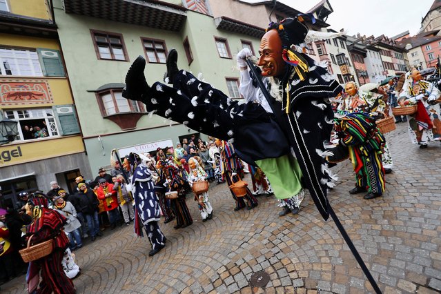 A carnival reveller swings around a long wooden stick and performs a vault, the so-called “Fools Jump”, during the traditional folklore procession “Narrensprung” dating back to the 14th century as part of the Swabian-Alemannic Rose Monday celebrations in the Black Forest town of Rottweil, in south-western Germany on February 12, 2024. (Photo by Wolfgang Rattay/Reuters)