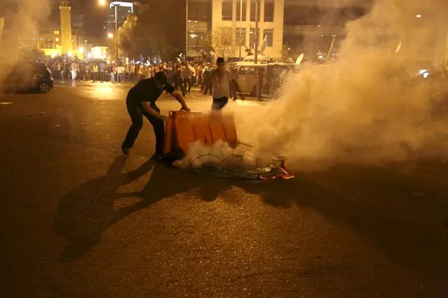 A protester tries to move a tear gas canister fired by security forces in Martyr square, downtown Beirut, Lebanon October 8, 2015. (Photo by Aziz Taher/Reuters)