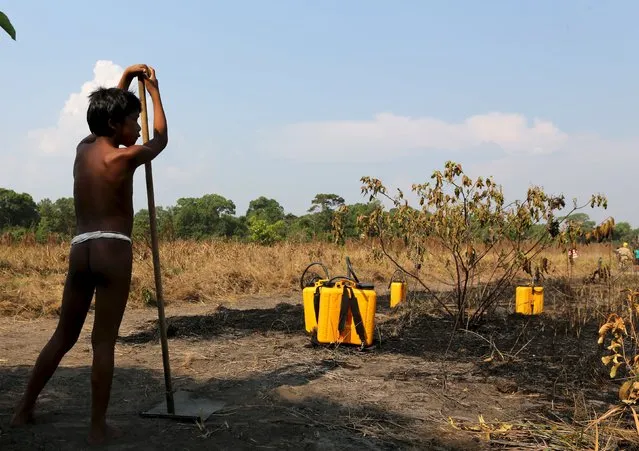 An indigenous boy stands next to equipment used to combat wildfire during a training at the Kamayura tribe, in the Xingu National Park, Mato Grosso, Brazil, October 3, 2015. (Photo by Paulo Whitaker/Reuters)
