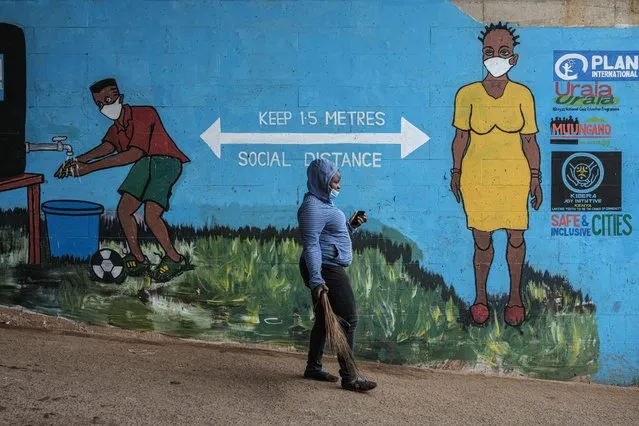 A woman with a face mask walks past graffiti that promotes social distancing, to curb the spread of the COVID-19 coronavirus, in Kibera, Nairobi, on July 15, 2020. (Photo by Yasuyoshi Chiba/AFP Photo)