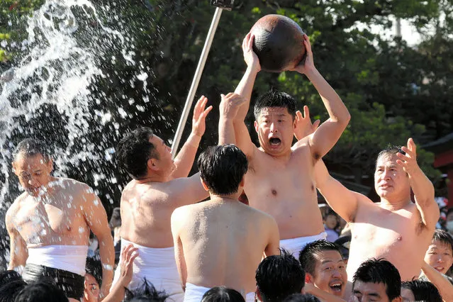 Participants wearing only loincloths compete to get hold of a wooden ball, which is believed to bestow good luck to those who touch it, while getting splashed with cold water in the Tamaseseri festival at Hakozakigu Shrine on January 3, 2023 in Fukuoka, Japan. The ritual also has a divination aspect to it, and participants are divided into “land” and 'sea' teams to forecast a successful harvest for the year. (Photo by The Asahi Shimbun via Getty Images)