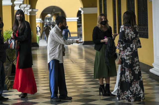 A beggar approaches a group of women wearing maks to curb the spread of the new coronavirus, as they were leaving a wedding ceremony near the Presidential Palace in Lima, Peru, Thursday, September 17, 2020. (Photo by Rodrigo Abd/AP Photo)