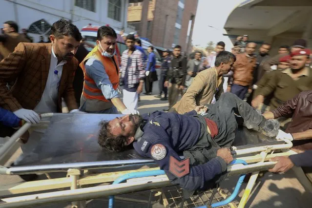 Workers and volunteers carry an injured victim of a suicide bombing upon arrival at a hospital in Peshawar, Pakistan, Monday, January 30, 2023. (Photo by Muhammad Sajjad/AP Photo)