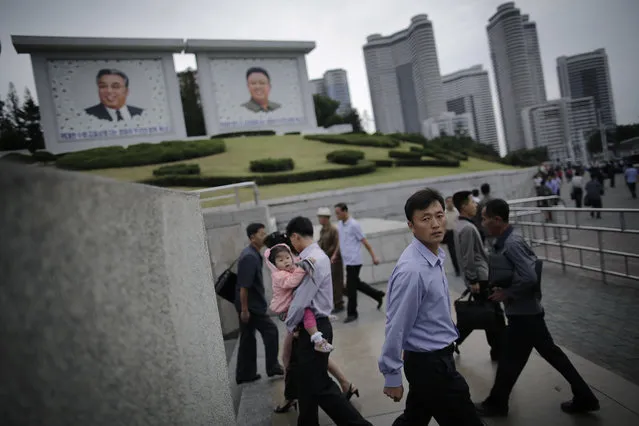 North Koreans walk in and out of an underpass leading to a subway station during morning rush hour while seen in the background are portraits of their late leaders Kim Il Sung, left, and Kim Jong Il on Wednesday, September 28, 2016, in Pyongyang, North Korea. (Photo by Wong Maye-E/AP Photo)