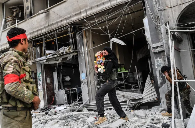 Turkish-backed Syrian rebels loot shops after seizing control of the northwestern Syrian city of Afrin from the Kurdish People's Protection Units (YPG) on March 18, 2018. In a major victory for Ankara's two-month operation against the Kurdish People's Protection Units (YPG) in northern Syria, Turkish-led forces pushed into Afrin apparently unopposed, taking up positions across the city. (Photo by Bulent Kilic/AFP Photo)