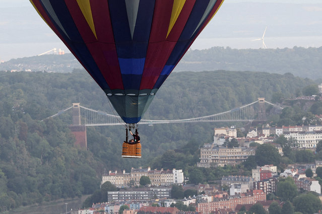 People look out of the basket of a hot air balloon as it flies, with Clifton Suspension Bridge in the background, during a mass launch at the annual Bristol International Balloon Fiesta, in Bristol, Britain, on August 8, 2025. (Photo by Toby Melville/Reuters)