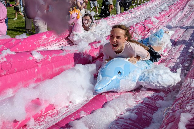 People slide down a water slide into a giant fake soup bowl during the Pink Soup Fest in Vilnius, Lithuania on June 1, 2024. Cold beetroot soup (saltibarsciai in Lithuanian) is a traditional Lithuanian dish usually served in summer and made with buttermilk or kefir, hard-cooked eggs, cucumbers, dill and pickled beetroot which gives the soup its bright pink color. Vilnius Pink Soup Fest is held this year for the second time and kick-start the summer season in the city. (Photo by Yauhen Yerchak/SOPA Images/Rex Features/Shutterstock)