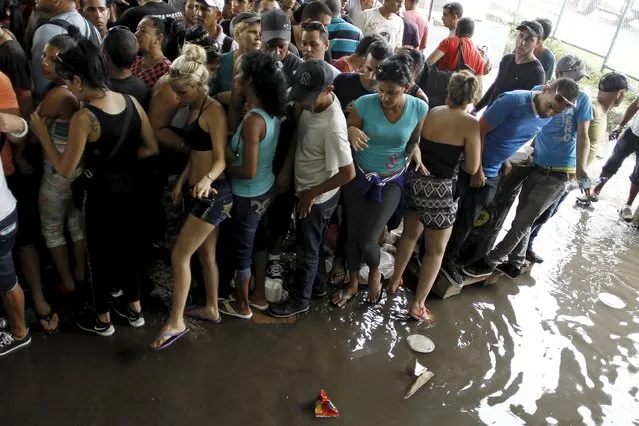 Cubans migrants evade a well of water caused by rain while waiting for a a humanitarian visa at a border post with Panama in Paso Canoas, Costa Rica November 14, 2015. (Photo by Juan Carlos Ulate/Reuters)
