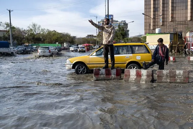 A traffic policeman gestures whilst on duty amid a flooded road in Kabul on April 3, 2023. (Photo by Wakil Kohsar/AFP Photo)