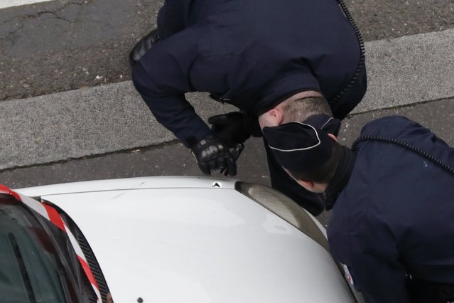 Policemen look at a bullet impact on a car after a shooting at the Paris headquarters of satirical weekly Charlie Hebdo, January 7, 2015. (Photo by Philippe Wojazer/Reuters)