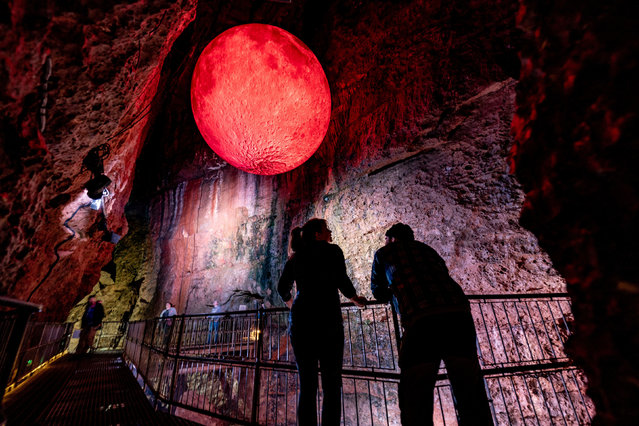 A couple look around Chamber 9 inside Wookey Hole caves, near Wells in Somerset, UK where a giant 5m wide blood moon hangs from the roof of the cave as part of Wookey Hole's annual celebration of Halloween events on Sunday, October 6, 2024. (Photo by Ben Birchall/PA Images via Getty Images)