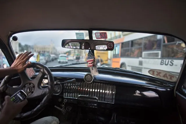 A taxi driver drives a vintage car in downtown Havana, January 16, 2015. (Photo by Alexandre Meneghini/Reuters)