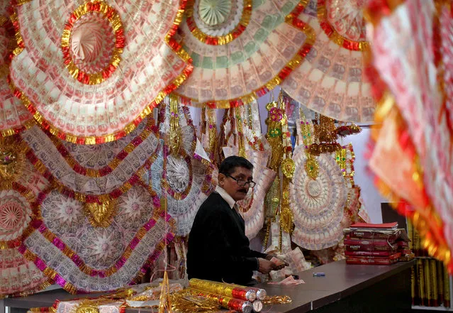 A shopkeeper prepares garlands of Indian currency notes at a shop in a market in Jammu, India November 14, 2016. (Photo by Mukesh Gupta/Reuters)