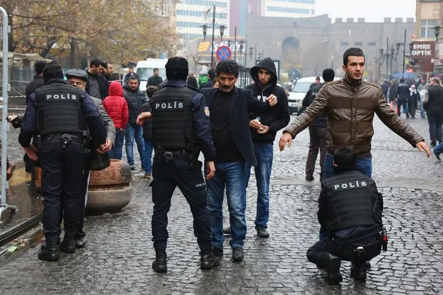 Police officers search civilians as they enter Sur district, which is partially under curfew, in the southeastern city of Diyarbakir, Turkey, December 30, 2015. (Photo by Sertac Kayar/Reuters)