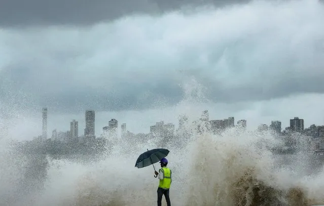 A construction worker watches as waves crash at coastal road construction site along a seafront, during high tide, in Mumbai, India on July 6, 2023. (Photo by Francis Mascarenhas/Reuters)