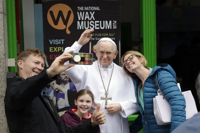 People take a selfie with a recently unveiled waxwork of Pope Francis displayed outside the National Wax Museum in Dublin, Ireland, Friday, August 24, 2018. Pope Francis arrives on Saturday for a two-day visit to Ireland. (Photo by Matt Dunham/AP Photo)