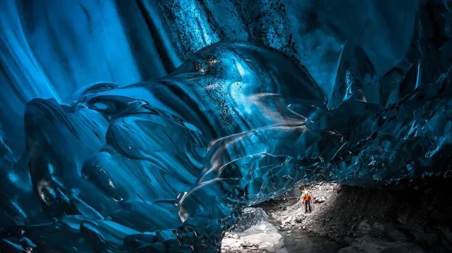Stunning images have revealed ice-cool British tourists chilling out inside Europe’s largest glacier – despite being at risk of flooding. The spectacular collection of images show the explorers braving the freezing temperatures to climb, photograph and even abseil down the inside of the icy cliff sides. Another image shows one visitor on his knees appearing to pray next to a water fall of melted ice. Other glistening shots show an adventurer trying to keep warm by a fire whose flames dance beautifully against the glossy roof. More shots show the caves sparkling like crystal with one ice formation appearing to resemble bubble wrap. In one picture, a brave tourist stands at the edge of a river flowing through the centre of the frosty caves. (Photo by Einar Runar Sigurdsson/Mediadrumworld.com)