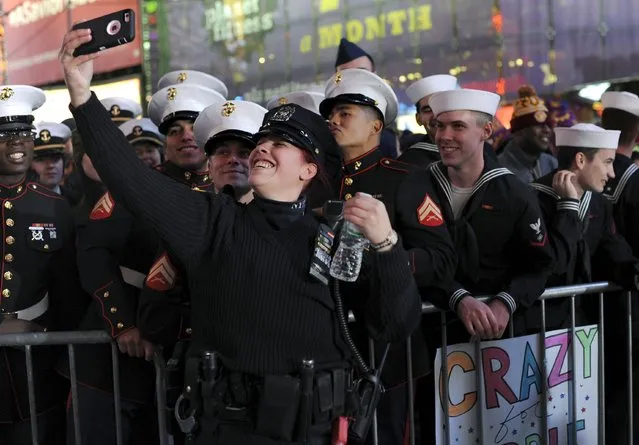 New York Police Department officer Nydia Rodriguez takes a selfie with members of the U.S. Marine Corps and U.S. Navy during New Year's celebrations in Times Square in the Manhattan borough of New York December 31, 2015. (Photo by Darren Ornitz/Reuters)