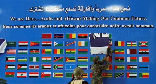 Anti-Gaddafi fighters deface a poster inside a hall of the Ouagadougou conference center as they celebrate the taking over of the building known for hosting regional conferences for Arab and African leaders in Sirte, Libya, October 9, 2011. (Photo by Asmaa Waguih/Reuters)