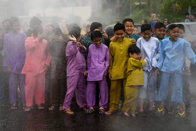 Malaysian boys are doused with water prior to a mass circumcision ceremony at the Bandar Tun Hussein Onn mosque in Kuala Lumpur on December 11, 2016. Young boys participated in a mass circumcision event amidst grand welcome and festivities, which some consider as a celebration of reaching manhood. (Photo by Manan Vatsyayana/AFP Photo)