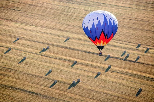 A hot air balloon flying over a field during the Russian Volga Federal District hot air balloon championships in Nizhny Novgorod Region, Russia on July 31, 2018. (Photo by Mikhail Solunin/TASS)