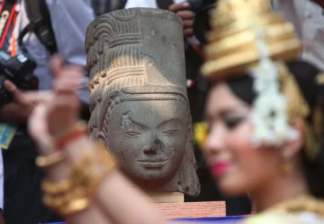 A dancer performs in front of the head belonging to the Harihara statue during a ceremony at Cambodia's National Museum in Phnom Penh January 21, 2016. French museum Guitmet handed over the head of Harihara statue to Cambodia on Thursday after being looted from its temple in Takeo province 130 years ago, according to media reports. (Photo by Samrang Pring/Reuters)