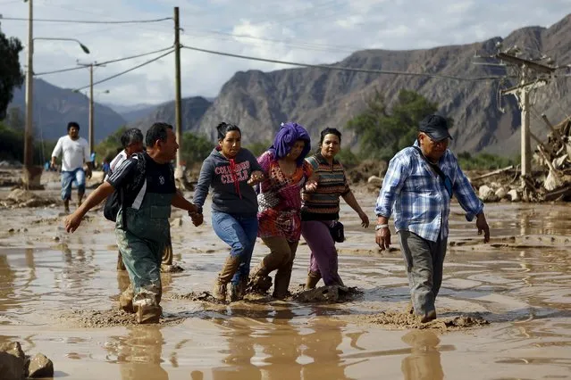 Locals cross a flooded street at Copiapo city, March 26, 2015. (Photo by Ivan Alvarado/Reuters)