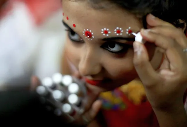An Indian girl, Aritri Bannerjee, gets dressed as the Goddess Durga, during the Kumari Puja as part of the Durga Puja festival at Shidaspur village, far north of Kolkata, eastern India, 22 October 2023. During the Kumari Puja, devotees worship a girl aged between six and twelve, symbolizing the Kanya Kumari (virgin) form of the Goddess Durga Devi. Hindu devotees believe that Kanya is a living embodiment of the goddess Durga. (Photo by Piyal Adhikary/EPA/EFE)