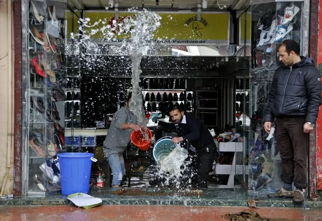 Kashmiri shopkeepers try to remove water from inside a footwear shop following heavy rains in Srinagar, Indian controlled Kashmir, Sunday, March 29, 2015. (Photo by Mukhtar Khan/AP Photo)