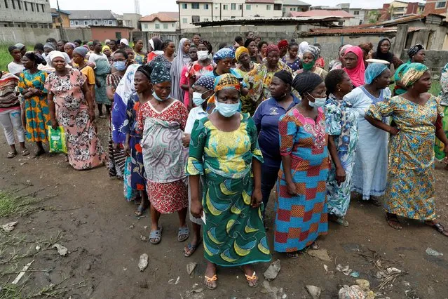 Women queue for food parcels during distribution by volunteers of the Lagos food bank initiative in a community in Oworoshoki, Lagos, Nigeria on July 10, 2021. (Photo by Temilade Adelaja/Reuters)