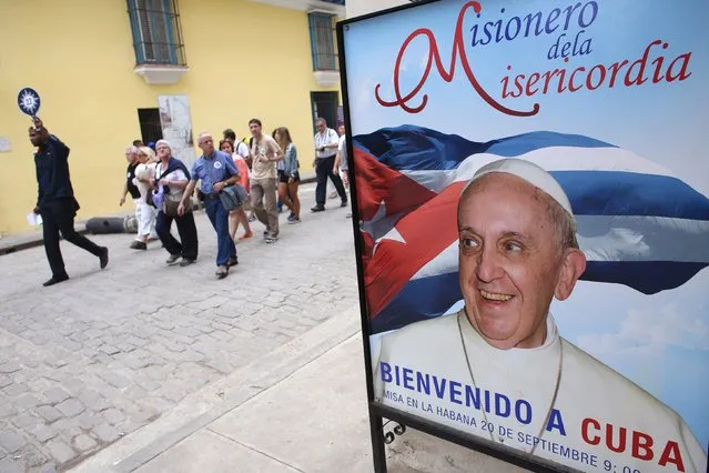 Tourists pass by a poster with a photograph of Pope Francis with the message in Spanish that reads “Welcome to Cuba”, Havana, February 10, 2016. Pope Francis and the head of the Russian Orthodox Church will meet in Cuba next week in what could be a landmark step towards healing the 1,000-year-old rift between the Western and Eastern branches of Christianity. (Photo by Alexandre Meneghini/Reuters)