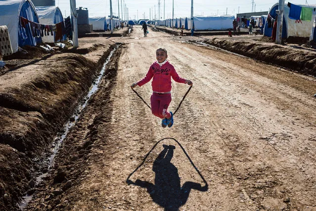 A displaced Iraqi girl, who fled the ongoing figthing between Islamic State (IS) group jihadists and government forces around Mosul, plays jump rope at the Khazer refugee camp near the Kurdish checkpoint of Aski kalak, 40 km West of Arbil, the capital of the autonomous Kurdish region of northern Iraq, on January 6, 2017. According to the UN, more than 125,000 people have fled their homes since the start of the offensive on October 17. Only 14,000 of them have been able to return to their homes in areas recaptured from IS, the UN Office for the Coordination of Humanitarian Affairs said. (Photo by Dimitar Dilkoff/AFP Photo)