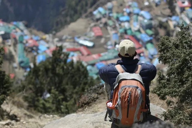 In this Monday, April 6, 2015 photo, a local Nepalese man sits above Namche, a village inhabited by mainly Sherpas, in the Everest region in Nepal. Climbers are returning to Mount Everest as the climbing industry recovers from last year's deadly disaster on the world's highest peak, a Nepalese mountaineering official said on April 1. The popular spring climbing season began last month and runs until the end of May. (Photo by Tashi Sherpa/AP Photo)