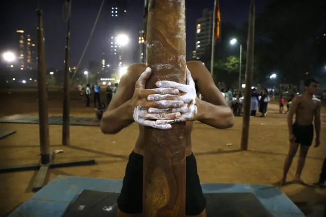 In this February 4, 2019, photo, a player tightens his grip on a mallakhamb pole as he trains at Shivaji Park in Mumbai, India. The word mallakhamb comes from malla, meaning wrestler, and khamb, or pole, and is a traditional training exercise for wrestlers in India. After centuries of being practiced in isolation in the subcontinent, mallakhamb is set to have its first international championship in Mumbai on Feb. 16 and 17. (Photo by Rafiq Maqbool/AP Photo)