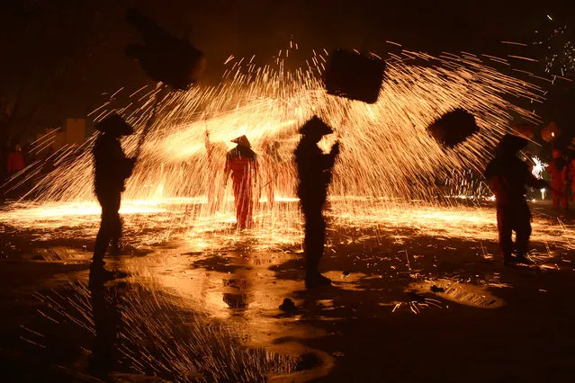 Folk artists holding lanterns perform under a shower of molten iron sparks during a local celebration ahead of the Chinese Lantern Festival, in Luzhou, Sichuan province, China on February 18, 2019. (Photo by Reuters/China Stringer Network)