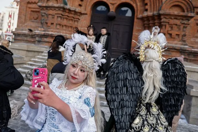 A woman wearing a costume takes selfies while waiting for a photo shooting session in front of the Saint Sophia Cathedral in Harbin, Heilongjiang province, China on January 5, 2024. (Photo by Tingshu Wang/Reuters)