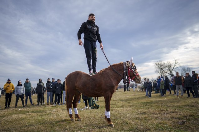 A man stands on a horse during Epiphany celebrations in the village of Pietrosani, Romania, Saturday, January 6, 2024. According to the local Epiphany traditions, following a religious service, villagers have their horses blessed with holy water and then compete in a race. (Photo by Vadim Ghirda/AP Photo)