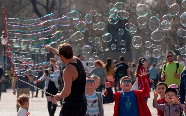 Children try to burst soap bubbles made by Polish busker Martin in front of the Slovak National Theatre in Bratislava, Slovakia on March 24, 2019. (Photo by Joe Klamar/AFP Photo)